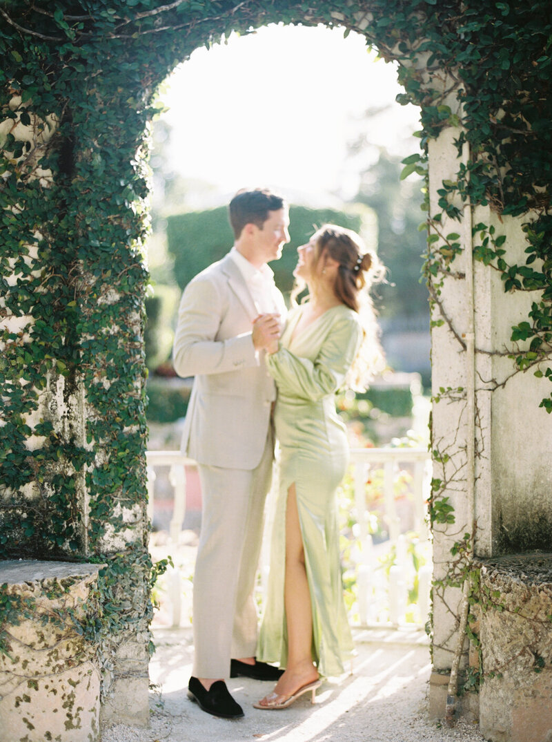 Couple laugh and dance during their engagement session on a sunny afternoon at Vizcaya Museum and Gardens in Miami
