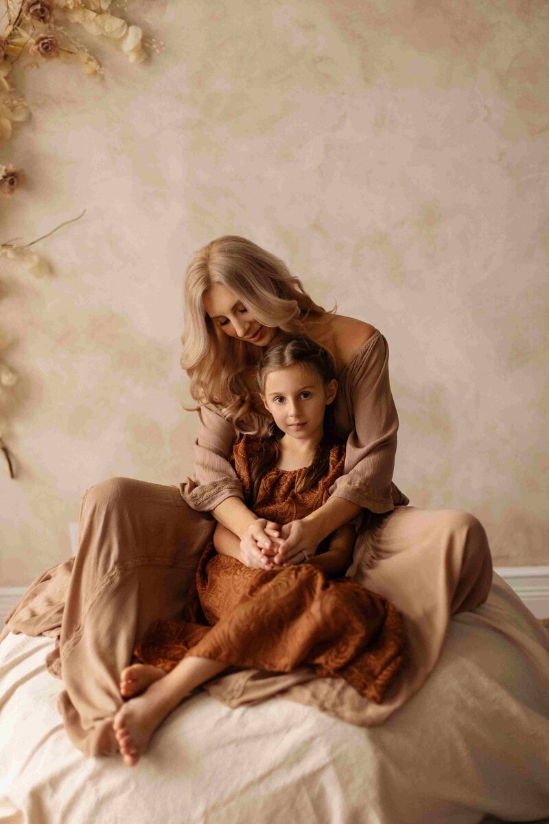 Portrait of parents holding their newborn baby, with their son leaning against them, gentle expressions, soft lighting