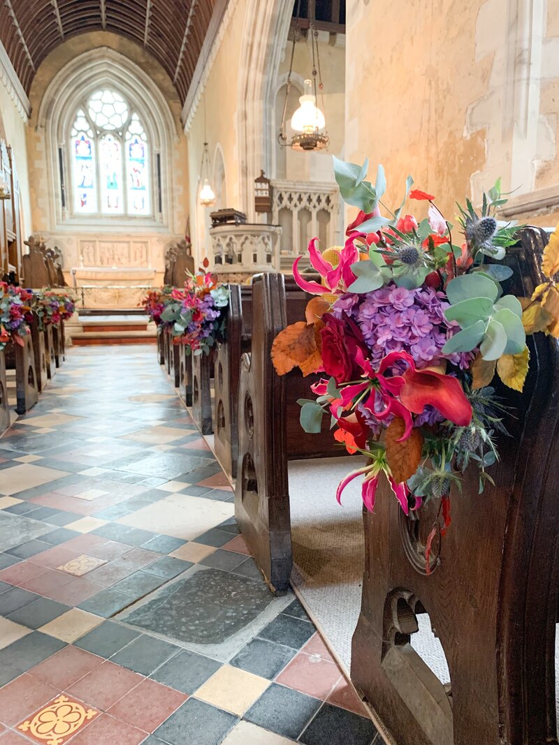 Church pews decorated with bright coloured flowers