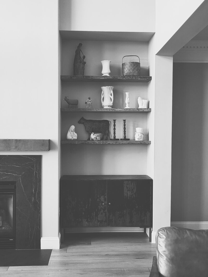 black and white photo of a fireplace nook with bookshelves and a cabinet
