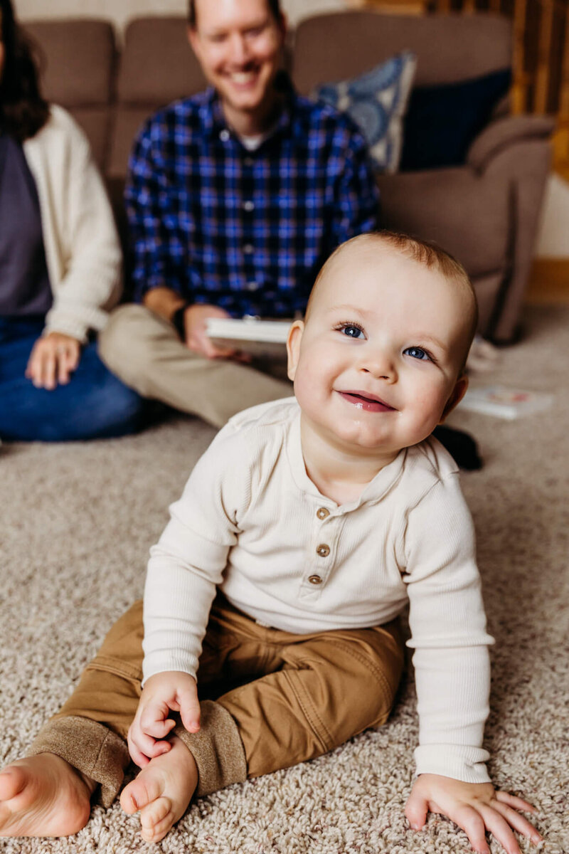 baby boy smiling for family photo session with dad smiling behind him
