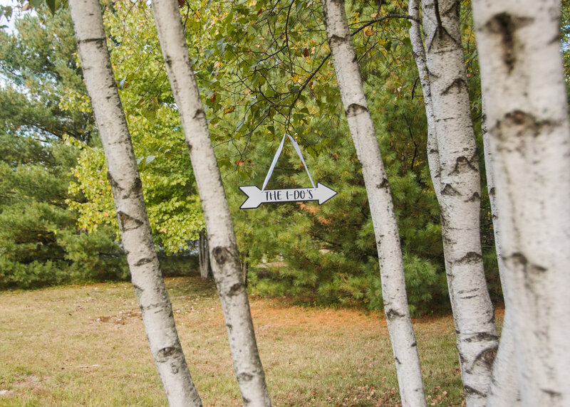 Intimate wedding bridal signage, hung on birch trees pointing to the altar in Northern Maine.