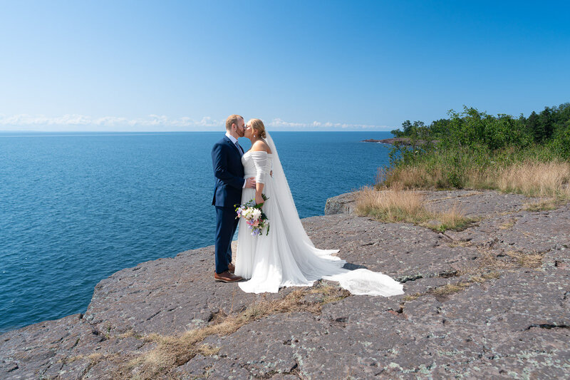 Bride and groom kiss at sunset in front of Lake Superior in Tofte, Minnesota.