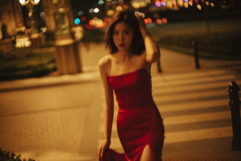 Destination couture photoshoot with a woman in. a red gown at night in the city.