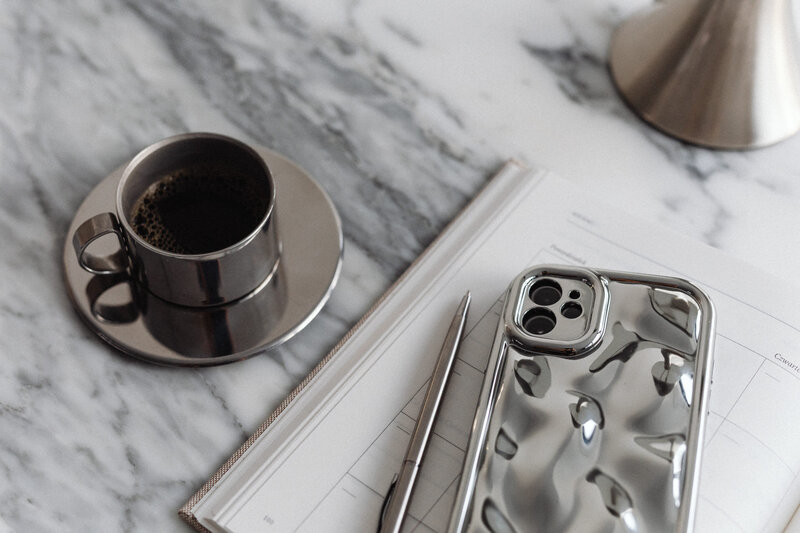 kaboompics_metal-desk-lamp-coffee-in-a-steel-cup-calendar-arabescato-marble-silver-phone-case-34135