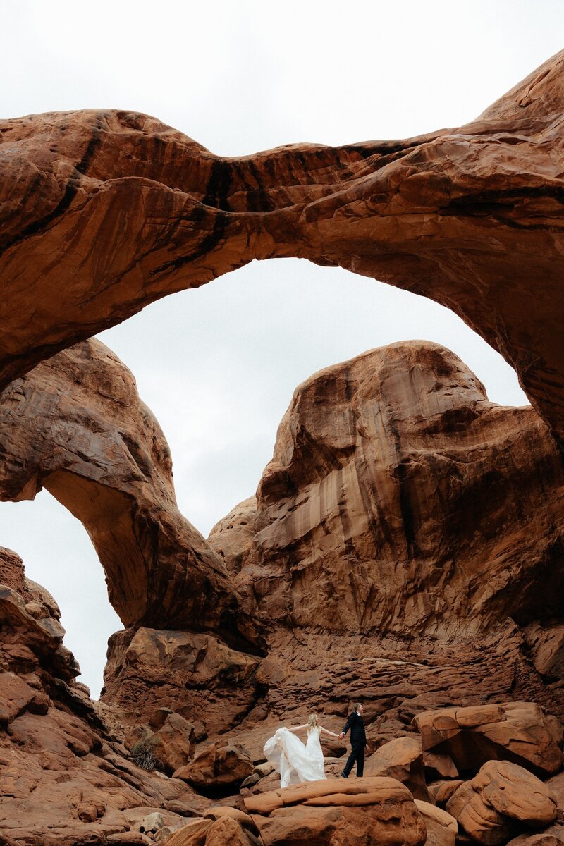 Couple holding hands on a black sand beach in Alaska.
