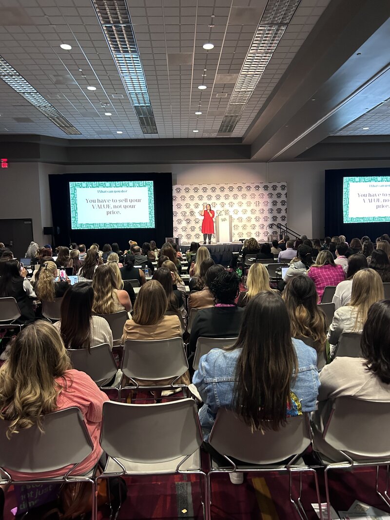 Renee Dalo gives a talk at a conference in audience-filled room