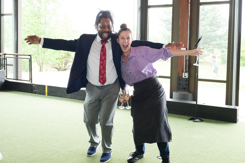 DJ Marz posing playfully with a guest indoors, both smiling with arms outstretched, showcasing his warm and energetic personality.