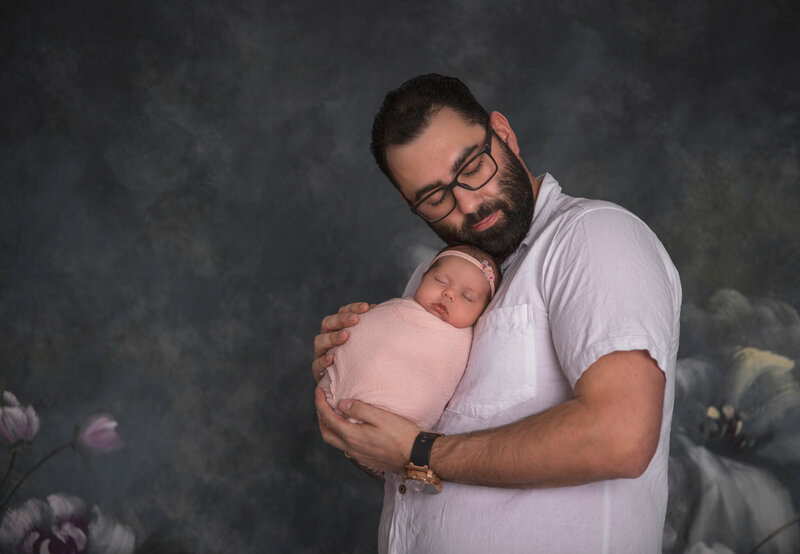  "A tender portrait of dad holding his newborn baby, captured in a peaceful and intimate moment during a fine art newborn photography session in Ottawa."
