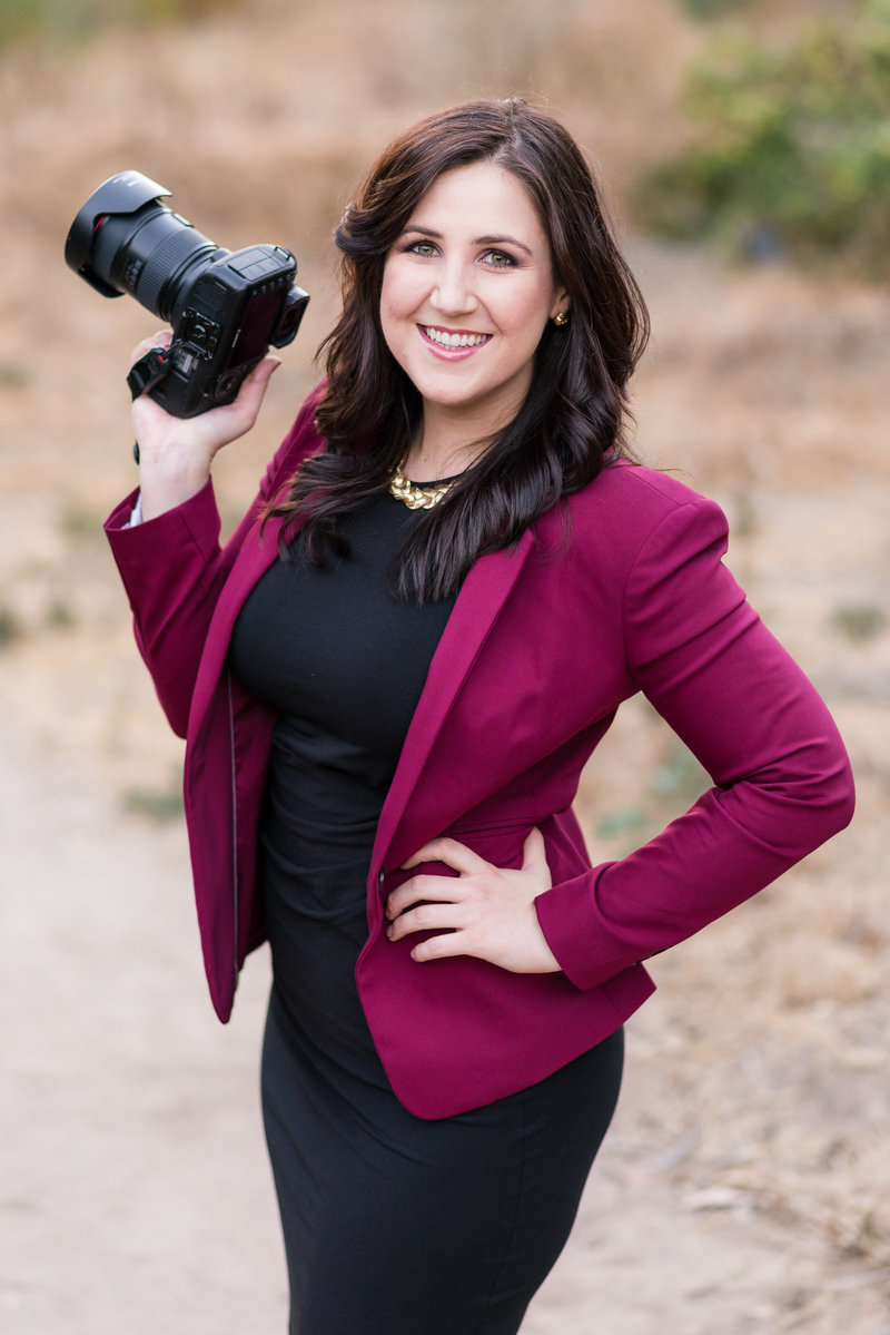 Wedding Photographer in Dallas Stefani Ciotti Photography holding camera with burgundy jacket and black dress