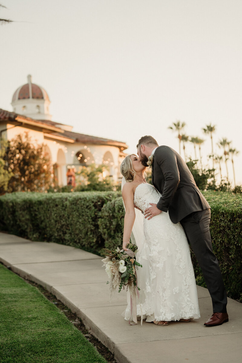 groom dips bride for a romantic kiss at spanish hills country club in camarillo