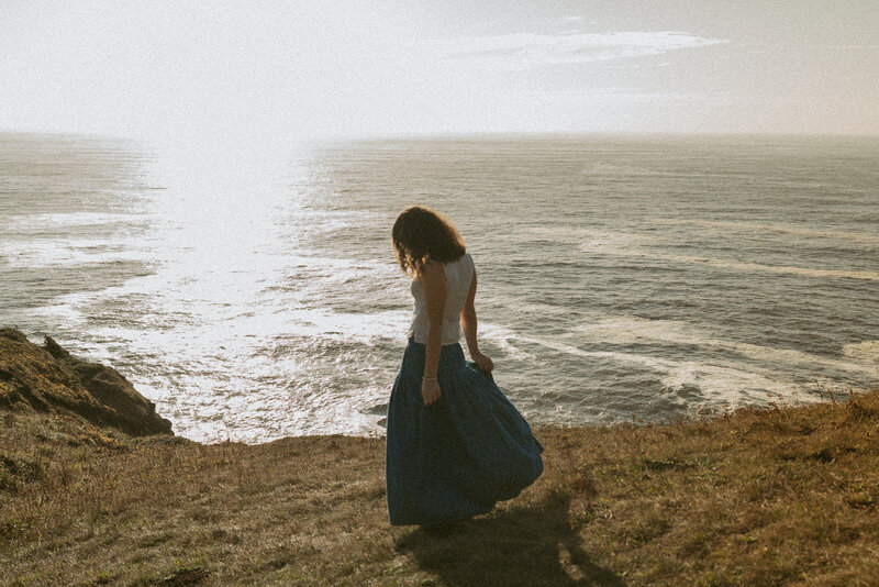 girl in white dress and sneakers standing on grassy path