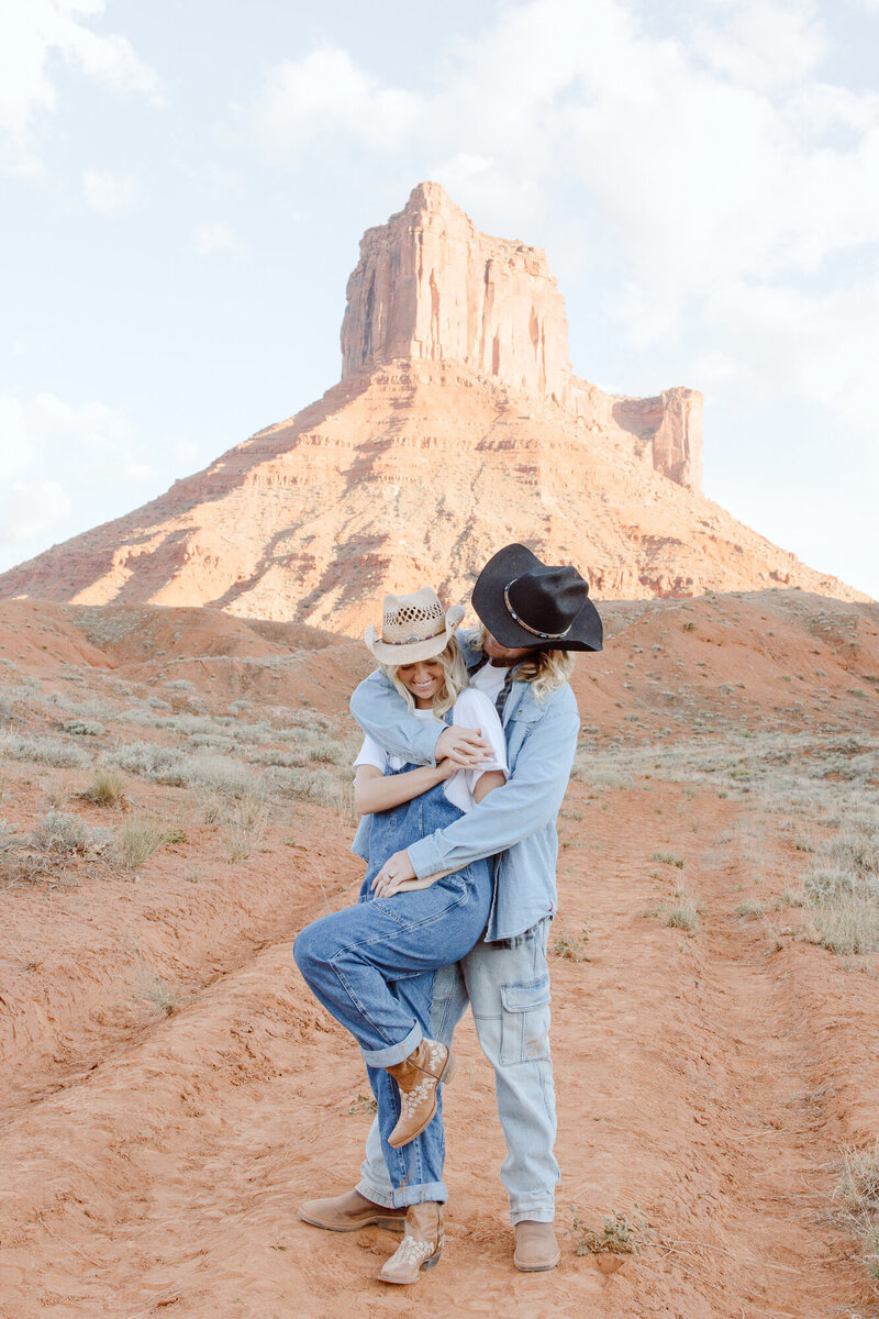 A couple tangled in each other's arms, wearing jean clothing, smiling in Utah