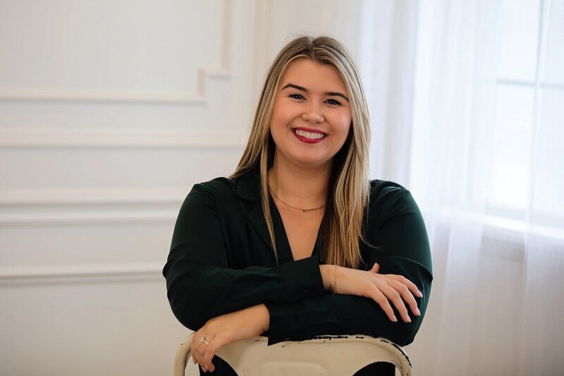 Karleigh Skeans sitting on a backwards chair with arms crossed and smiling.