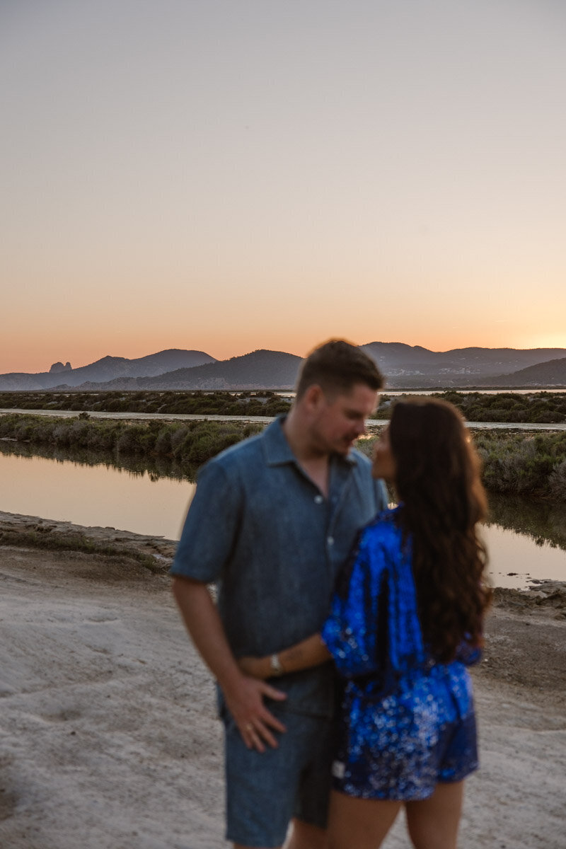 A pregnant woman dressed in white is looking down at her belly during a maternity photoshoot Ibiza.