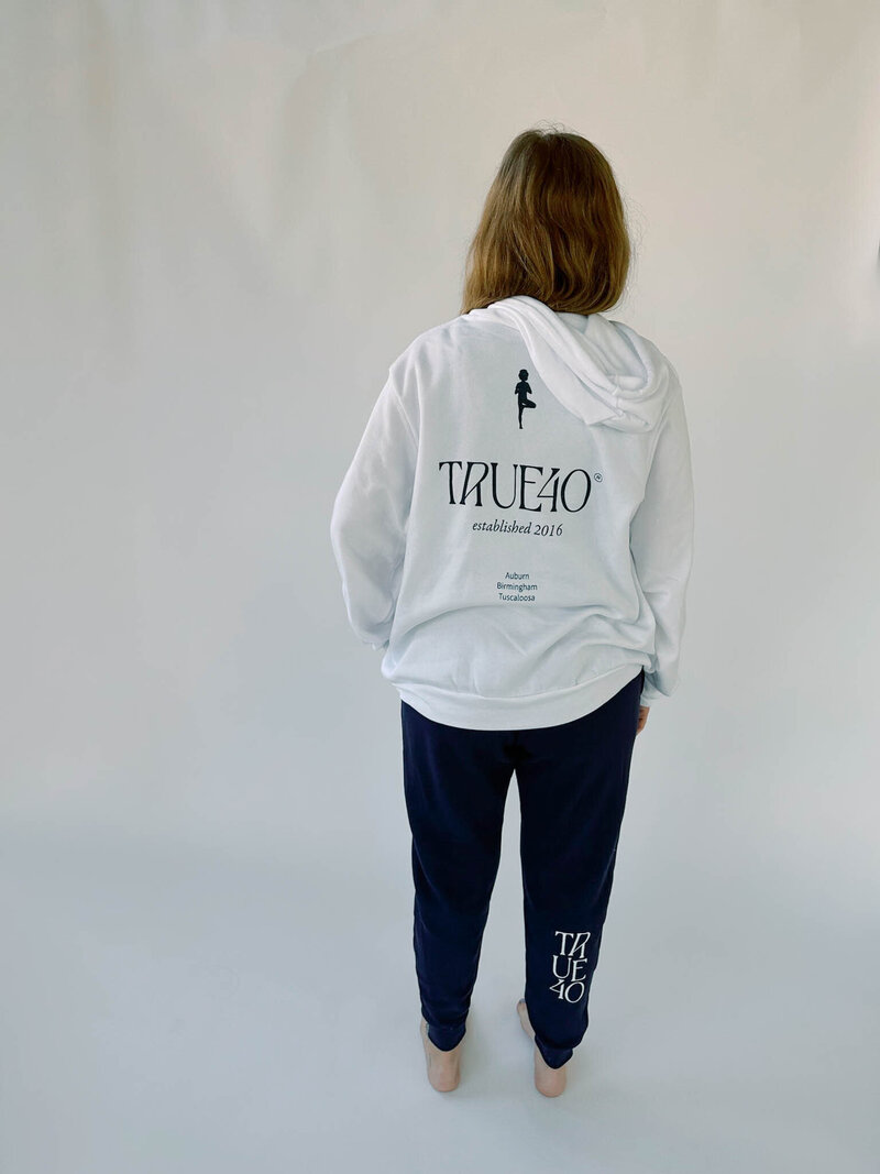 The back of a woman wearing the True40 locations hoodie