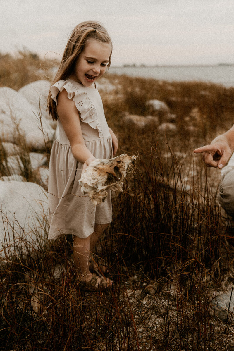 Little girl holding a skull she found at a photo session and looking surprised.