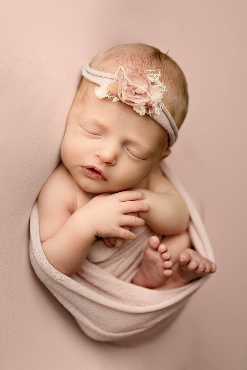 Portrait of newborn in bassinet surrounded by leaves and flowers