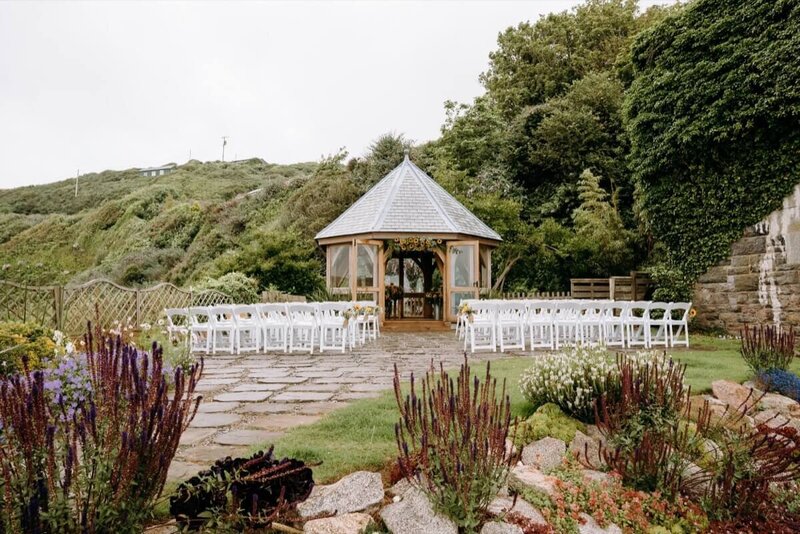 A beautiful summer house surounded by greenery and rows of white chairs