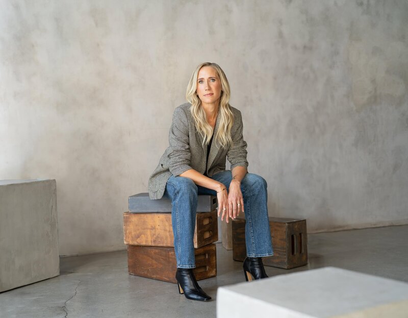 Nicole Woods sitting on wooden boxes at a photo studio looking at the camera