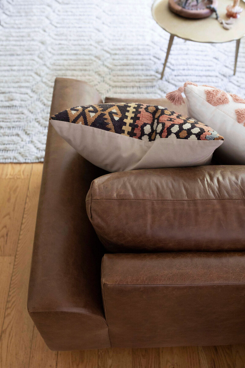 Close up of leather sofa and decorative throw pillows that create an organic modern aesthetic.