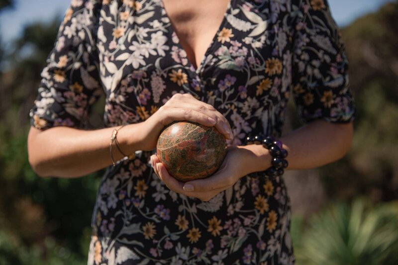 Lauren holding a large jade  sphere - which is our feng shui ball, out in the sun.