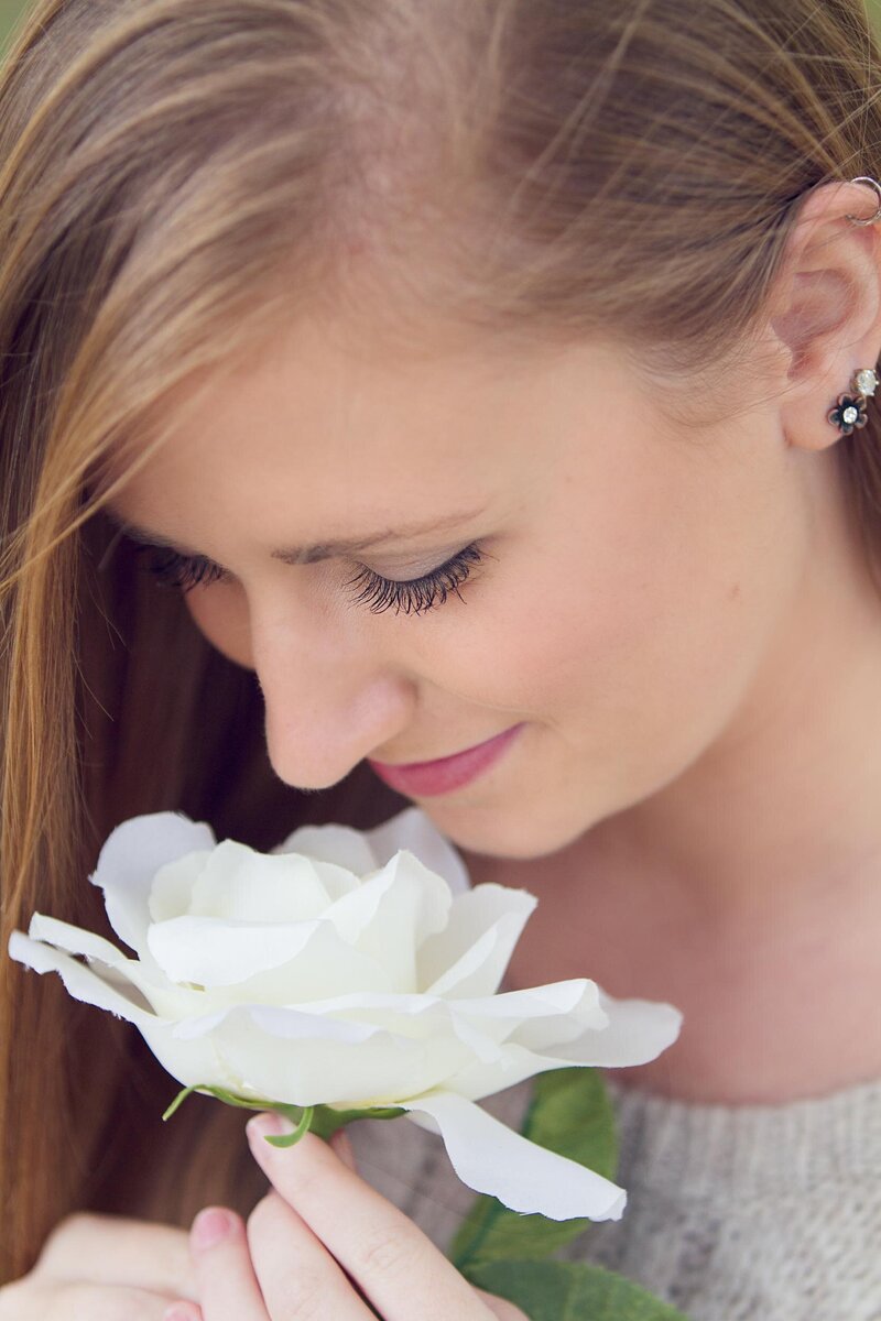 Senior portrait of a girl smelling a flower.