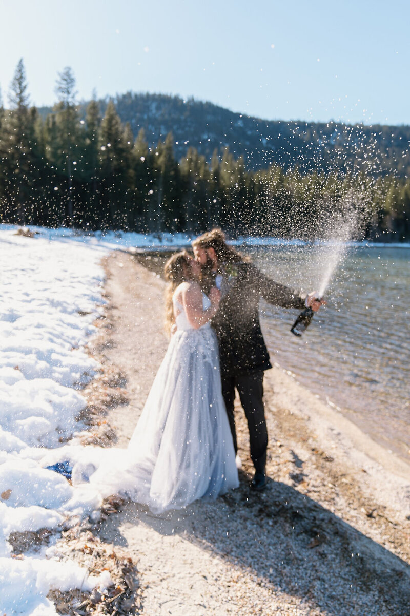 Bride & grooms kissing while spraying champagne at Lake Wenatchee in Leavenworth!