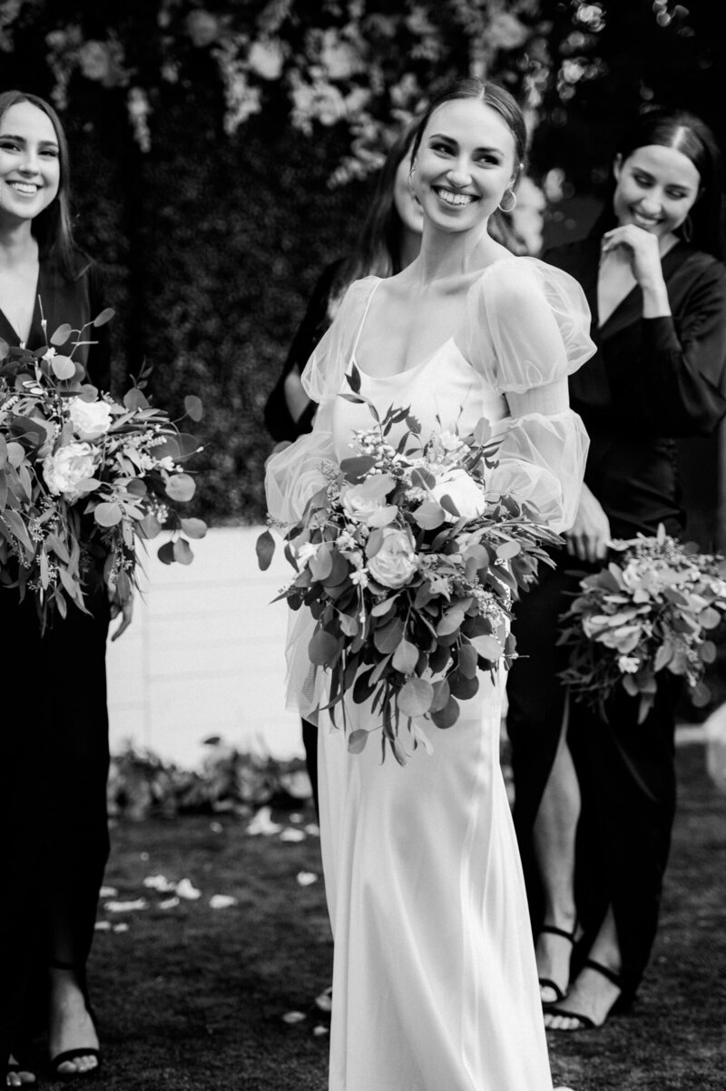 Bride laughing with bridesmaids behind her also laughing