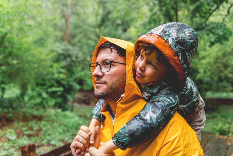 Father and son in forest in the rain