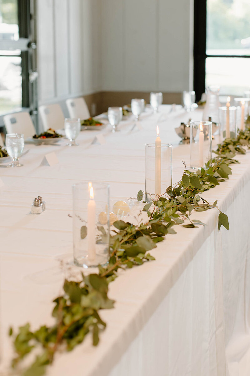 A close-up of a beautifully decorated head table at a wedding reception, featuring elegant florals, candles, and personalized touches. Girasole & Co. Weddings, the leading wedding planner in Columbus, Ohio, specializes in creating stunning, stress-free weddings tailored to your vision. Let us help you design the perfect wedding day, from décor to coordination, with expert planning and attention to detail.