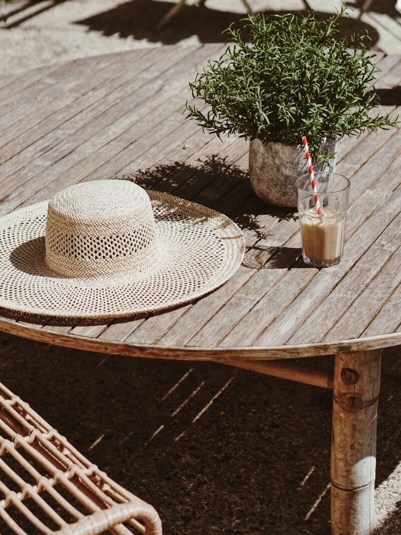 Straw hat on table with iced coffee - tales of adventure