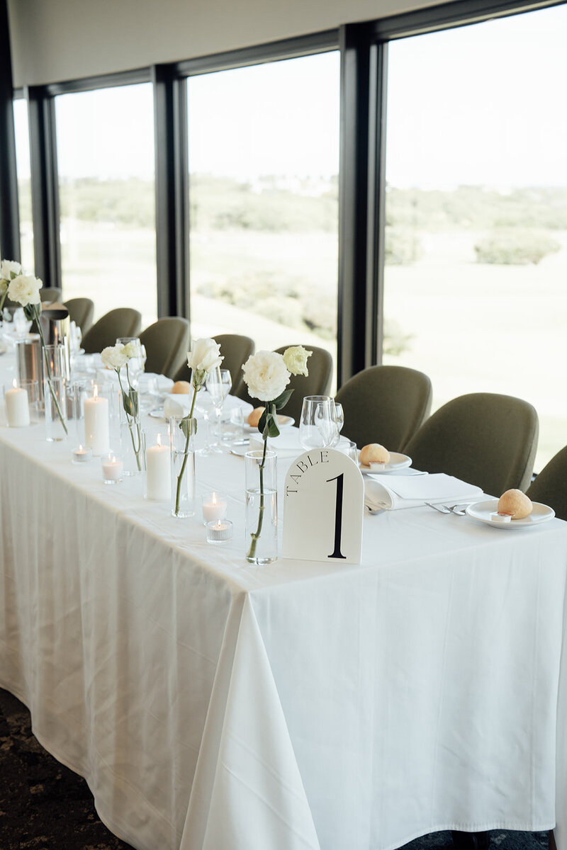Wedding reception Long rectangle tables styled with candles and white rose bud vases at the Warrnambool Golf Club