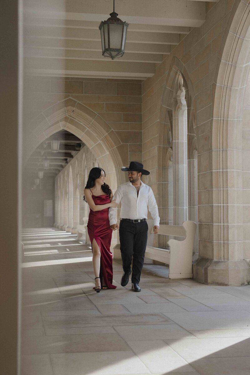Man wearing hat and woman wearing red dress walking