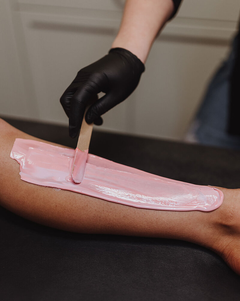 Esthetician applies wax to a woman's leg for hair removal