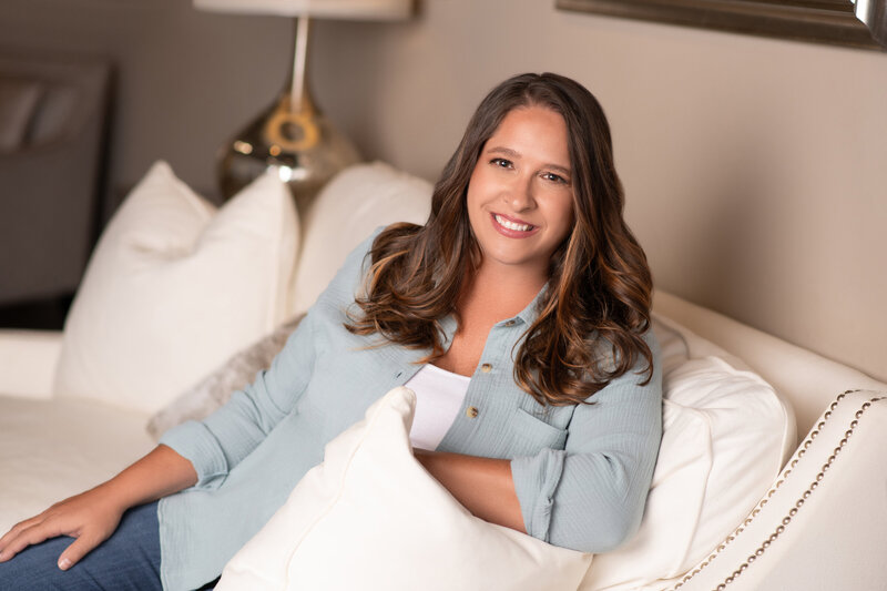 Woman long hair smiling with head tilted sideways sitting on a white couch