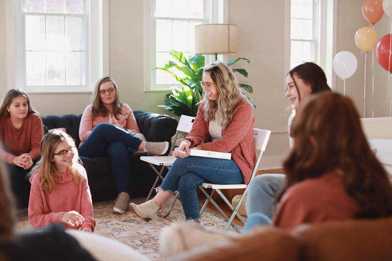 woman teaching teenage girls in living room setting