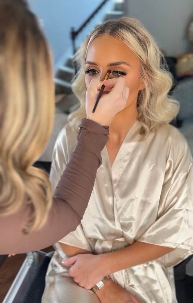 A makeup artist applying makeup to someone's eyes.
