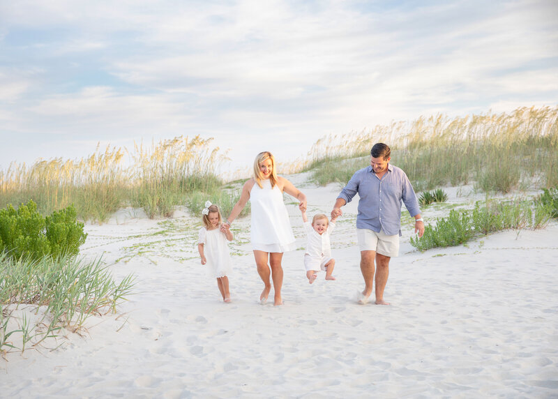 family of four photographed in the beach dunes on st simons island with sea oats in the background