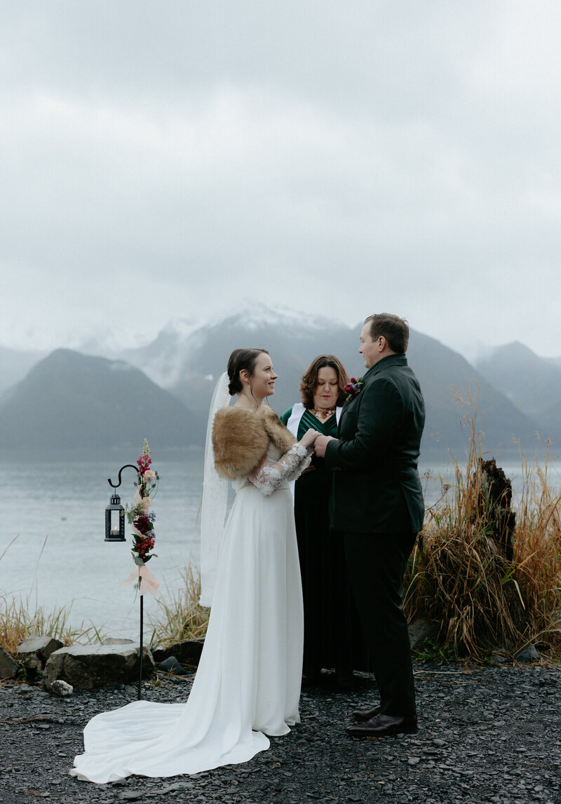A woman placing a ring on a mans finger. 
