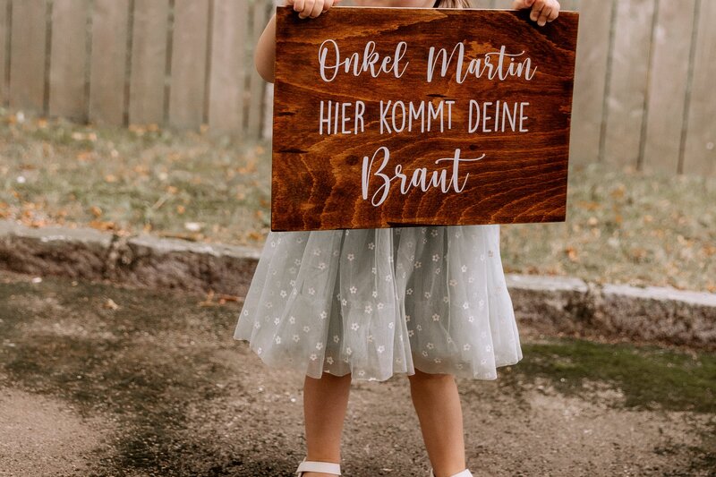 Kind haelt Schild mit der Aufschrift Onkel Martin hier kommt deine Braut