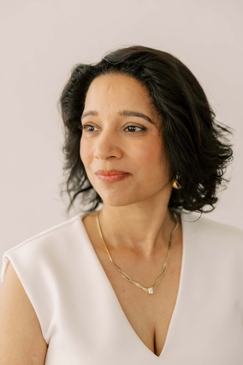Indian woman wearing gold jewelry and soft smiling to the distance