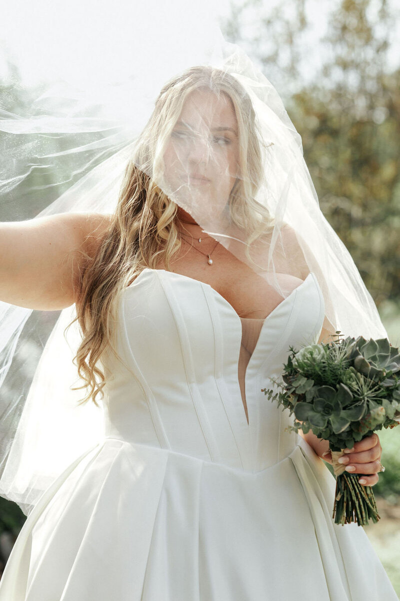 Bride holding veil and succulent bouquet