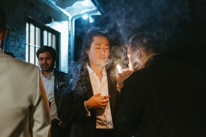 Groomsmen light celebratory cigars during the reception of their wedding. 