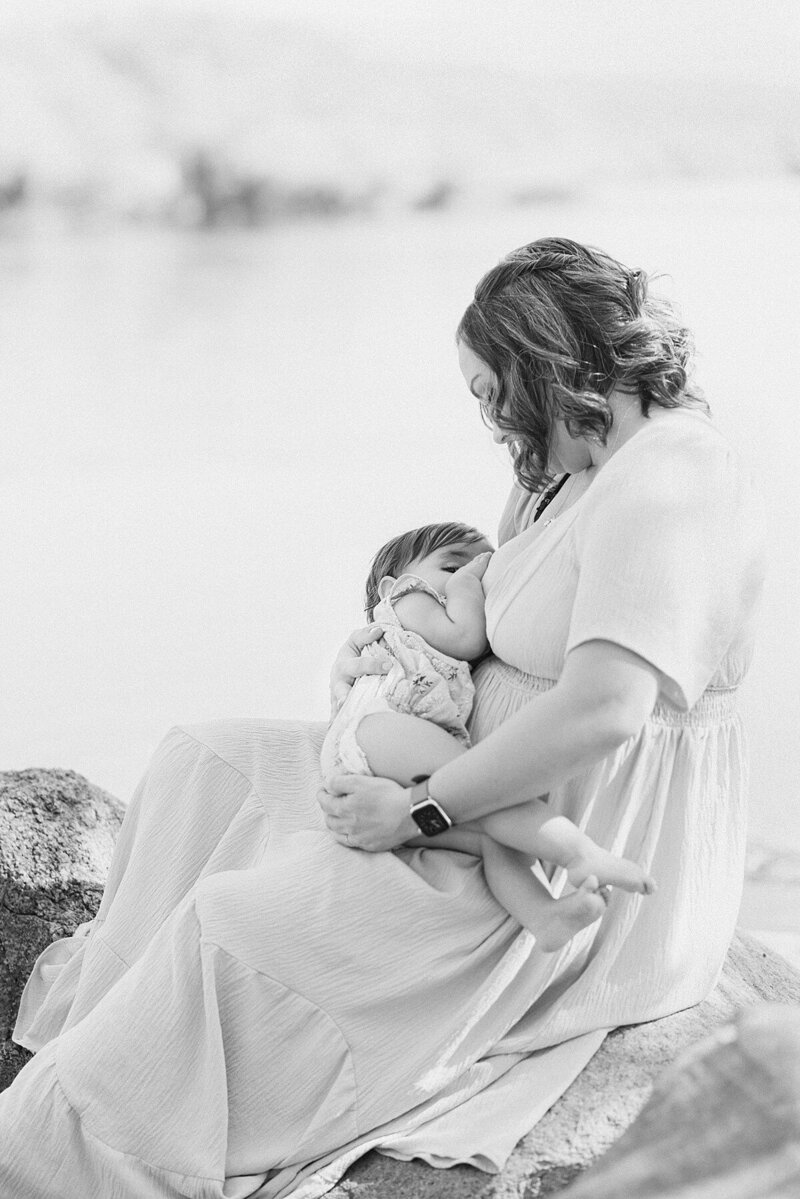 New mom with eyes closed holding sleeping newborn on shoulder and facing camera.