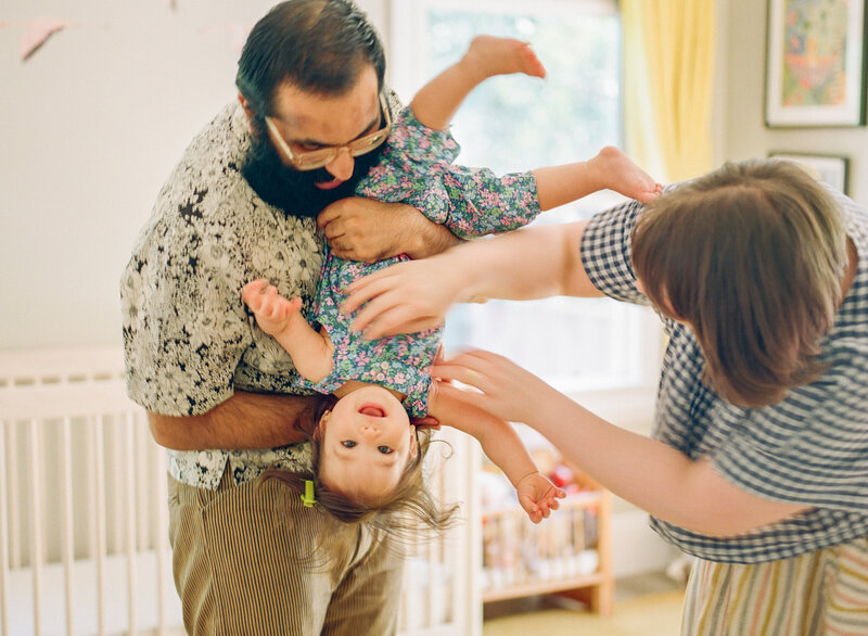 film photograph of two parents holding toddler girl upside down