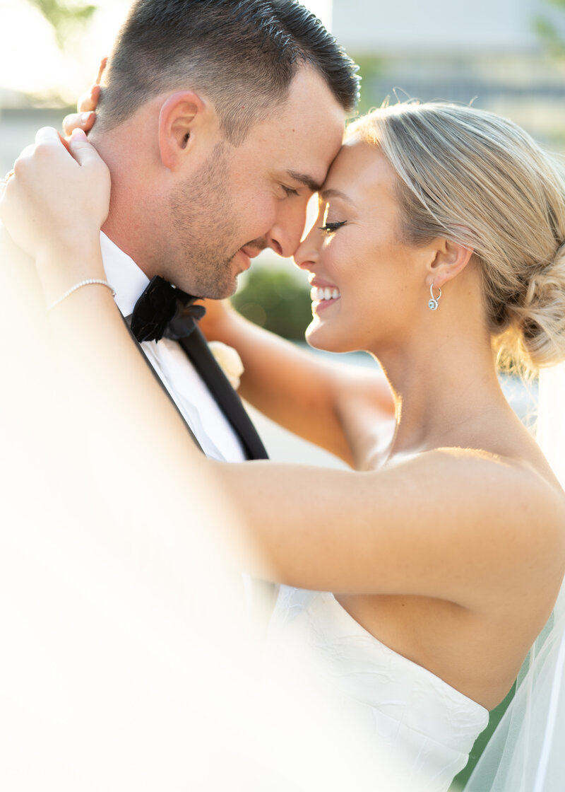 Bride and groom embrace forehead to forehead smiling on their wedding day