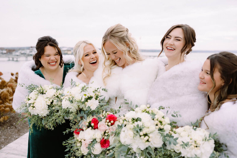Bride with bridesmaids wearing fluffy covers at winter wedding at Finger Lakes,  New York