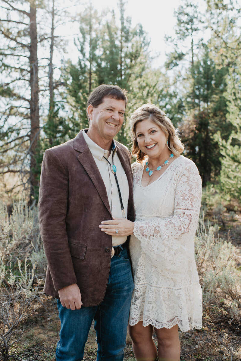 wedding portrait by jackson hole wedding  photographers with bride and groom  posing with a woods in the distance