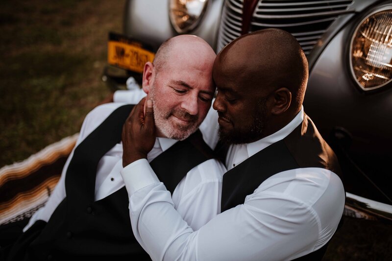 Two grooms embracing during sunset.